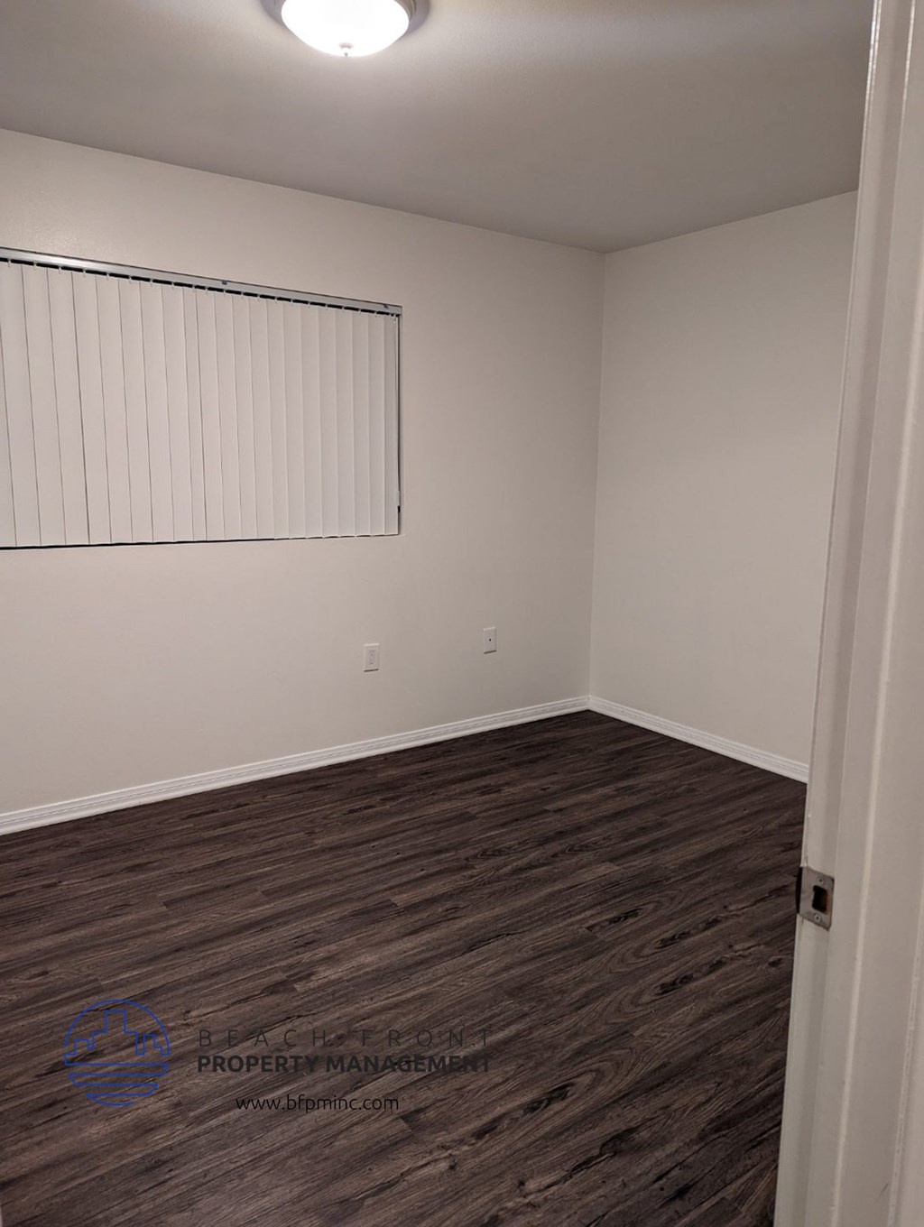 an empty room with wood flooring and a window